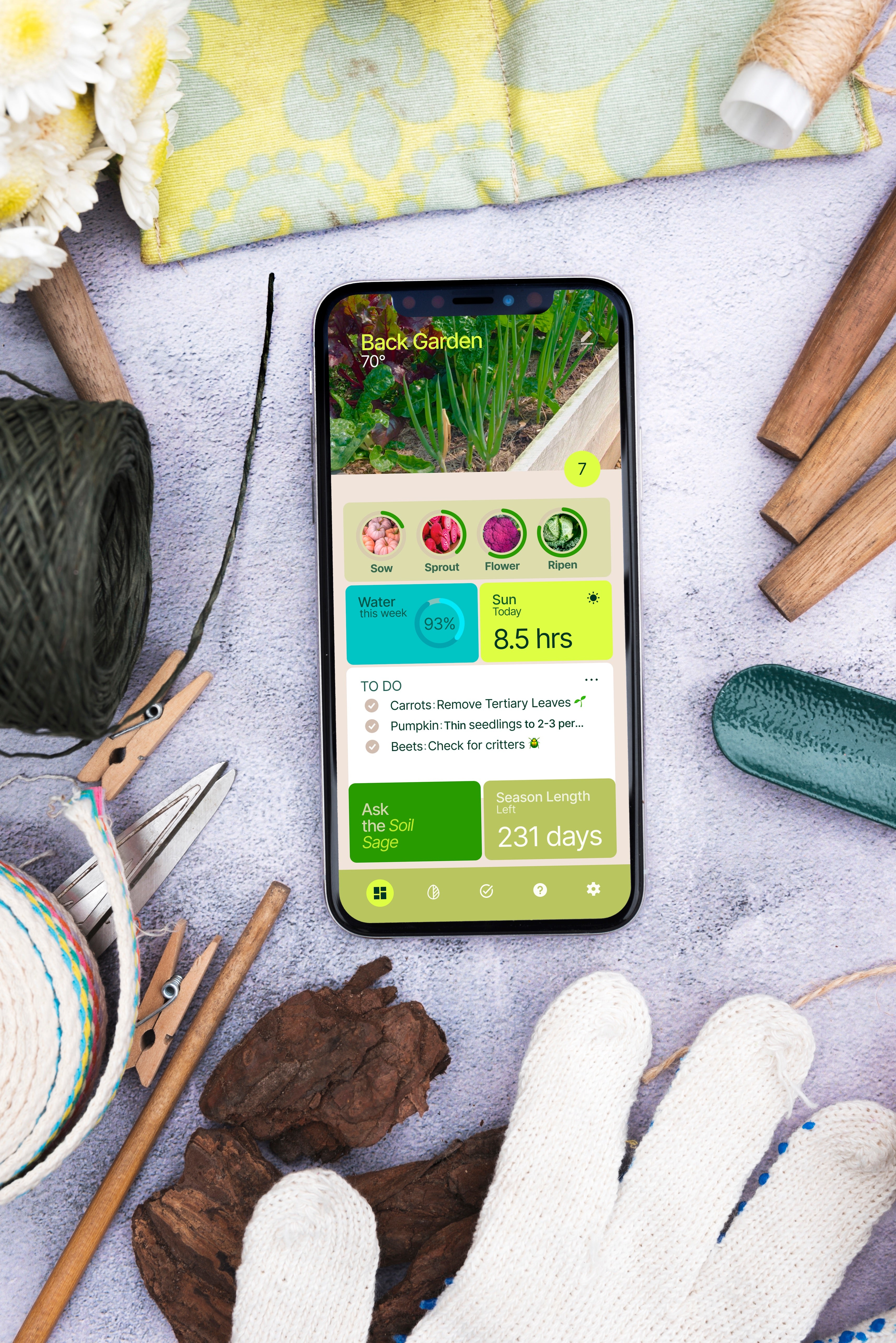 Smartphone displaying a IndieFarmer app surrounded by vegetable gardening tools 