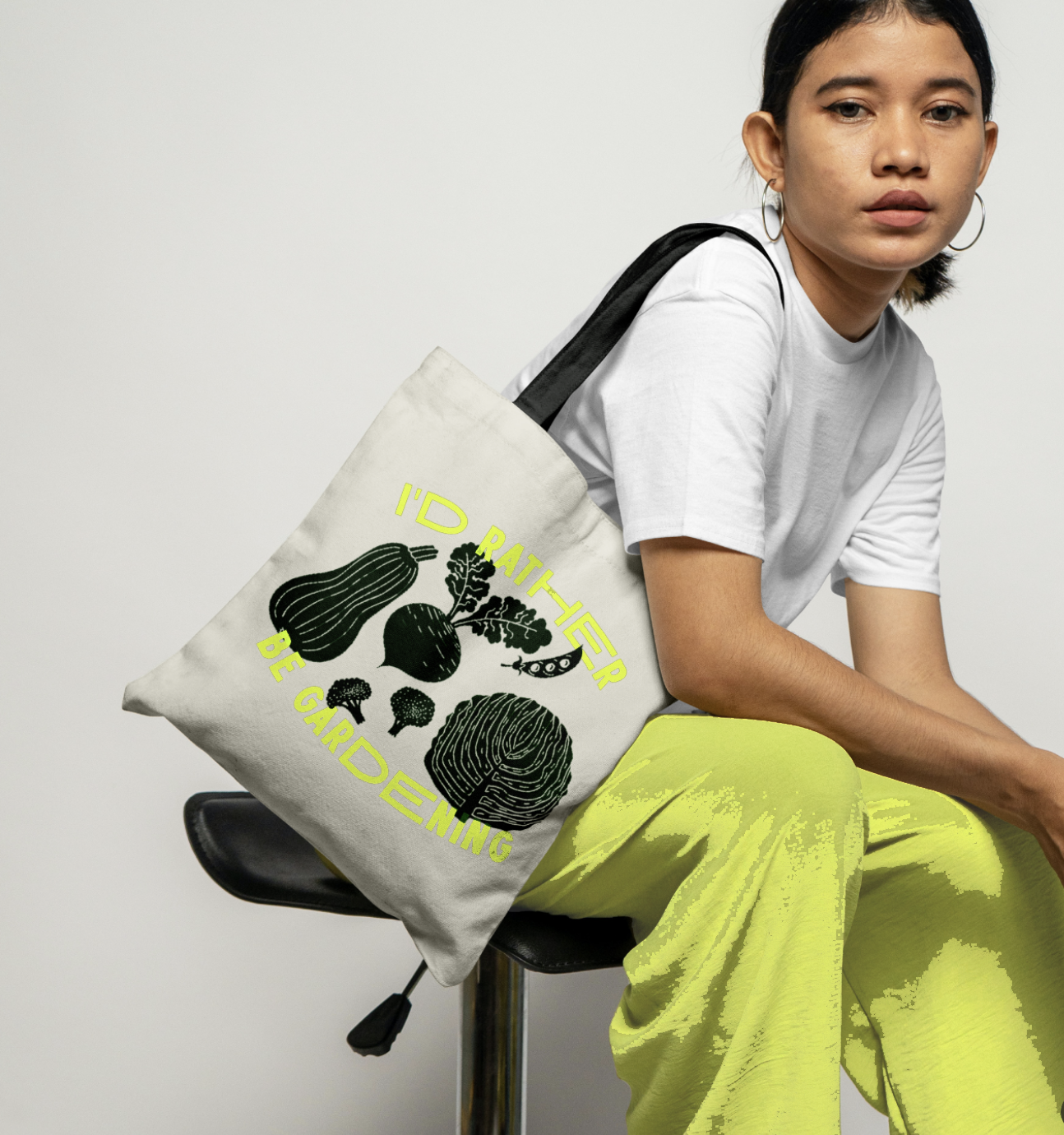 Person holding a tote bag with gardening design and text.